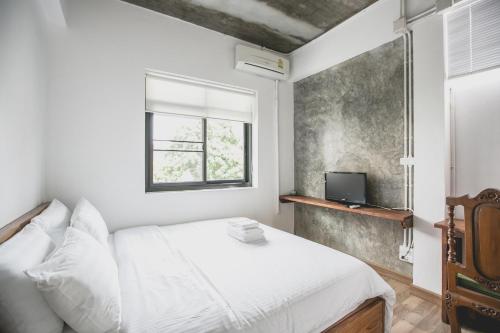 a bedroom with a white bed and a window at Plern Plern Bed and Bike in Chiang Mai
