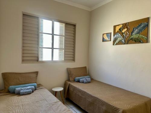 two beds in a room with a window at Apartamento Central in Passos