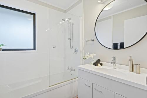 a white bathroom with a sink and a mirror at Suthar's Home in Wellington
