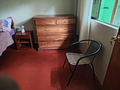 a bedroom with a dresser and a chair and a desk at Posada del Carmen 2 in Quillabamba