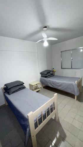 a bedroom with two beds and a ceiling fan at Apartamento no centro de Mongaguá in Mongaguá