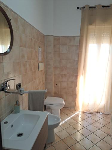 a bathroom with a toilet and a sink and a mirror at La Piuma in Misterbianco