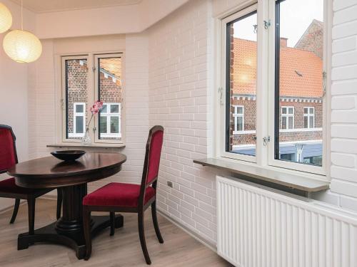a dining room with a table and chairs and windows at Charming Retreat in Ringkobing in Ringkøbing