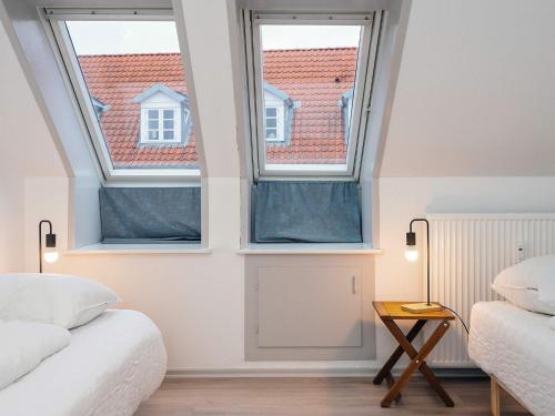 two windows in a room with two beds and a table at Charming Retreat in Ringkobing in Ringkøbing