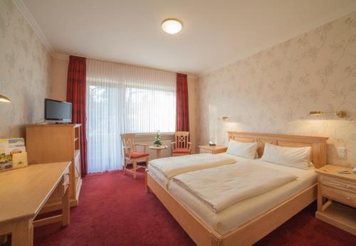 a hotel room with a bed and a table and a desk at Hotel Backenköhler in Ganderkesee
