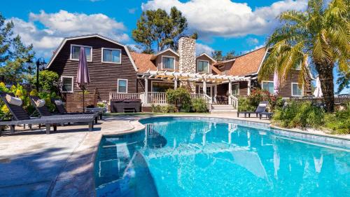 a house with a swimming pool in front of a house at Chateau Syrah by AvantStay Picturesque Estate w Pool Hot Tub Table Tennis Pool Table New Pickleball Court Basketball hoop in Temecula