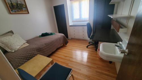 a small room with a bed and a sink at Pells Hostel in Regina
