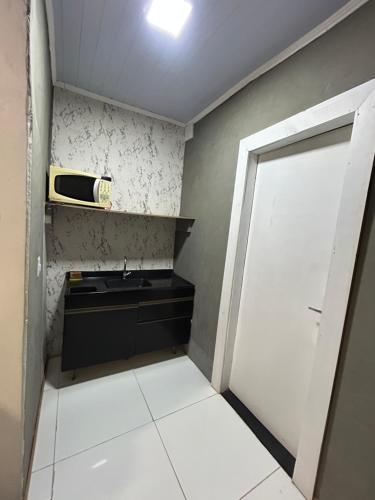 a small kitchen with a sink and a door at Loft fundos shopping Catuai e lago in Cascavel