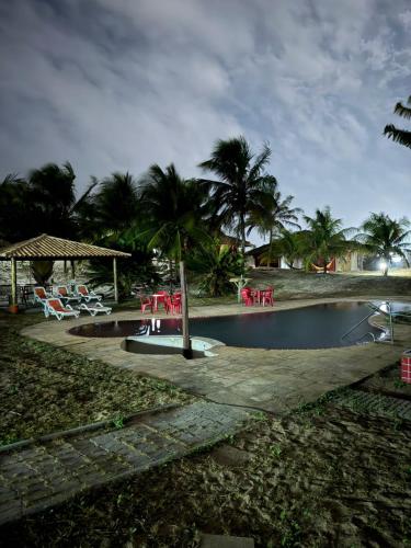 a pool with red tables and chairs and palm trees at Apoena in Conde