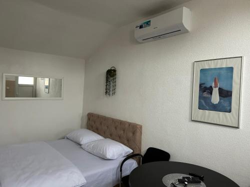 a bedroom with a bed and a table and a air conditioner at Apartmani BALKAN in Sjenica