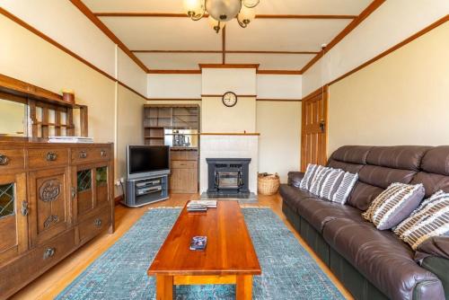 a living room with a leather couch and a table at Kurow Escapes - Holiday Home in Kurow