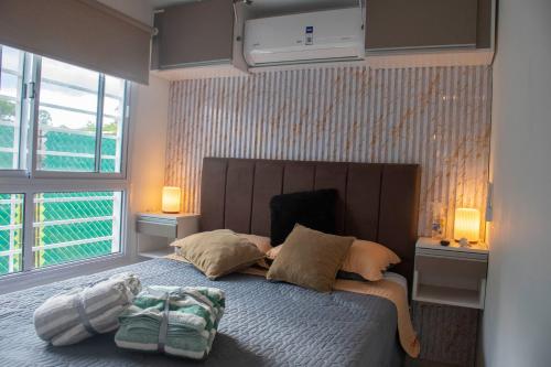 a bedroom with a bed with two pillows and two windows at Refugio Lagunas in San Antonio