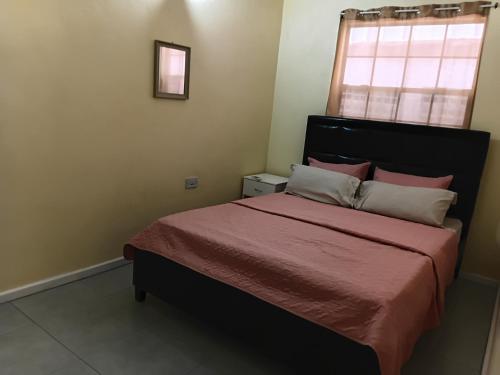 a bedroom with a bed with a red bedspread and a window at Southern Haven Guesthouse in Laborie