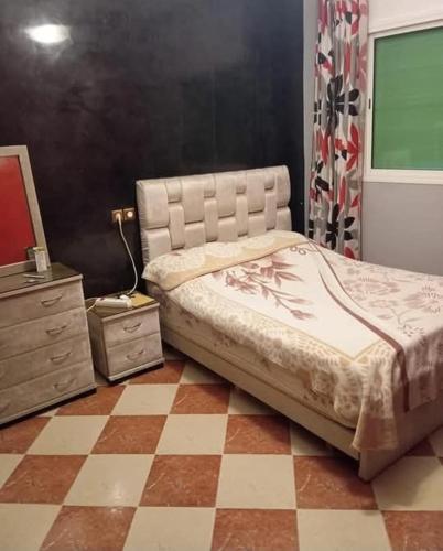 a bedroom with a bed and a checkered floor at Maison zakaria in Meknès