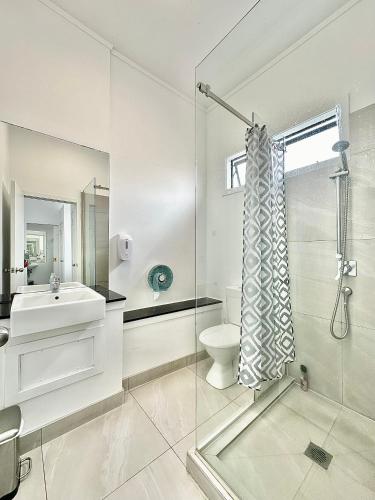 a white bathroom with a shower and a toilet at SpinCity Lodge Auckland in Auckland