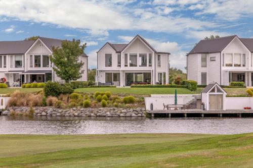 a large house on the water with a dock at Clearwater Golf Resort - Entire Luxury Home in Christchurch