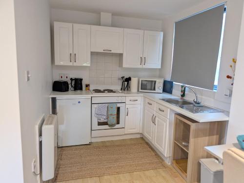 a small kitchen with white cabinets and a sink at Studio Apartment - Iver Heath in Uxbridge