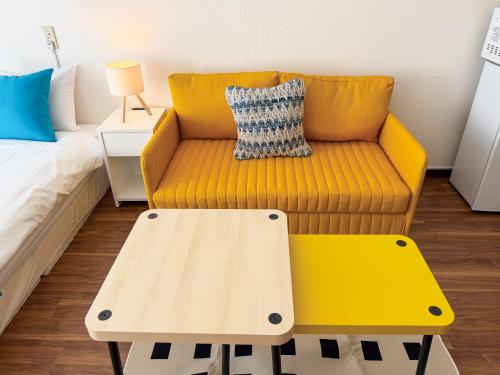 a yellow couch and a table in a room at BALCOM STAY Hiroshima Takasu in Hiroshima