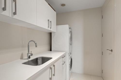 a white kitchen with a sink and a refrigerator at Clearwater Golf Resort - Entire Luxury Home in Christchurch