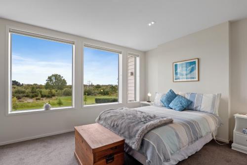 a bedroom with a bed and a large window at Clearwater Golf Resort - Entire Luxury Home in Christchurch