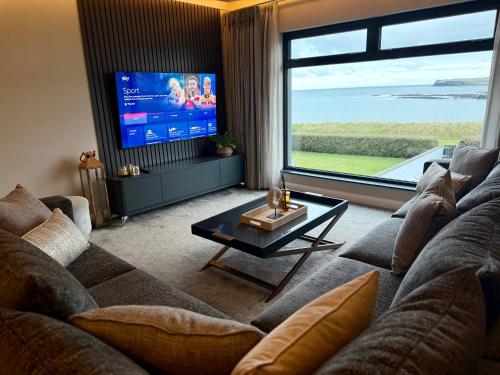 a living room with a couch and a flat screen tv at Shoreline Portballintrae North Coast Views Near Giants Causeway & Royal Portrush in Portballintrae