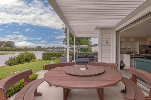 a patio with a wooden table and chairs at Clearwater Golf Resort - Entire Luxury Home in Christchurch