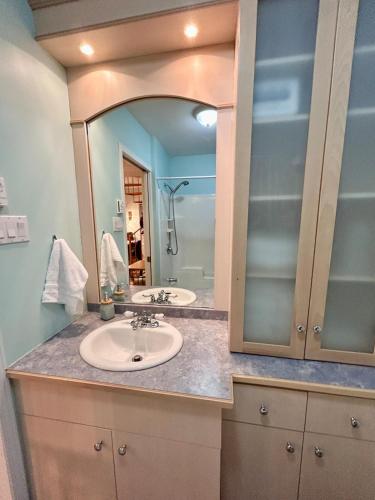a bathroom with two sinks and a large mirror at La Cachette in LʼAnse-Saint-Jean