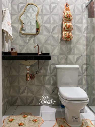 a bathroom with a toilet and a mirror and a sink at BECA Residencial in Canoa Quebrada