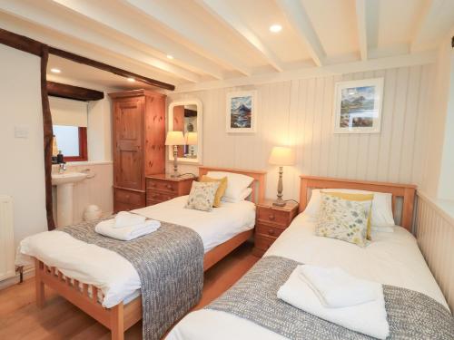 a bedroom with two beds and a mirror at Jasmine Cottage in Keswick