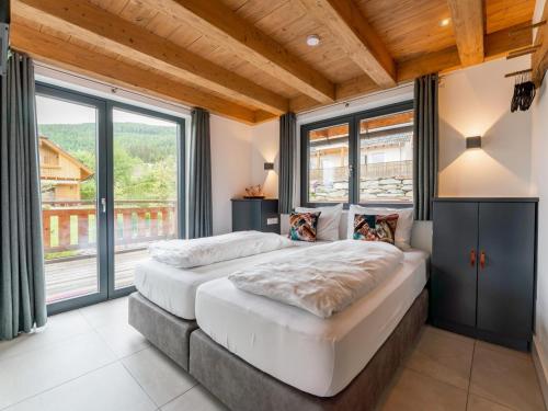 two beds in a room with large windows at Alpinn Wellness 2 in Sankt Margarethen im Lungau