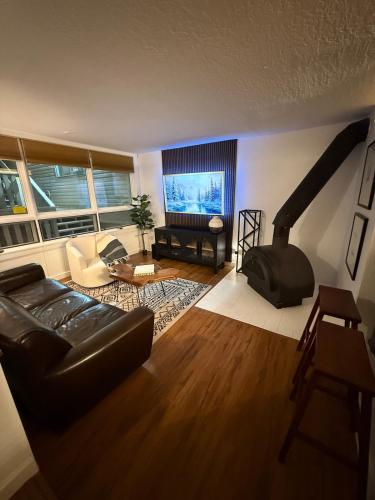 a living room with a black couch and a fireplace at High Pines Haven in Angel Fire