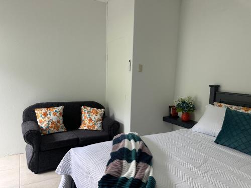a living room with a bed and a chair at Villa Nola Tres in Port-of-Spain