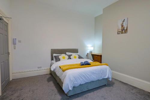 a bedroom with a bed with a yellow blanket on it at Elevate suites Darlington in Darlington