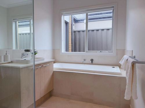 a bathroom with a tub and a sink and a window at Modern Home Canal Berwick in Berwick