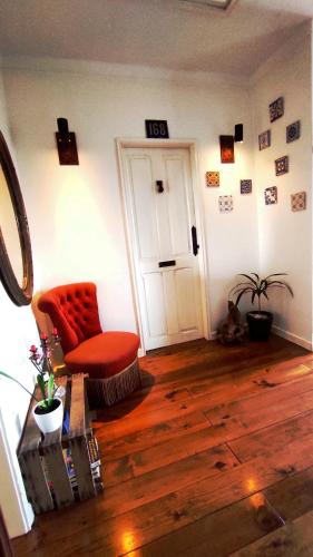 a living room with a red chair and wooden floors at DockApartment in Vila Nova de Gaia
