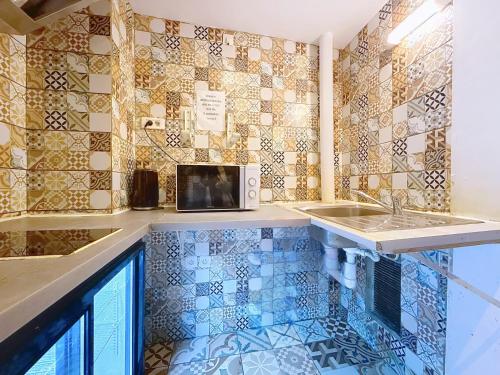 a kitchen with a sink and a microwave on a tiled wall at Au Fleuri hotel in Paris