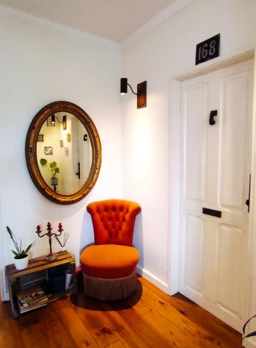 an orange chair sitting in a room with a mirror at DockApartment in Vila Nova de Gaia