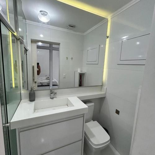 a white bathroom with a sink and a toilet at Lindo studio no Residencial Quisisana in Poços de Caldas
