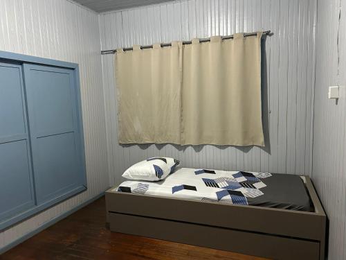 a bedroom with a bed with a curtain and a window at Cantinho do Descanso in Cascavel