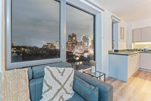a living room with a blue couch and a large window at Luxury Highrise Flat Wembley Stadium & Event Stay in London