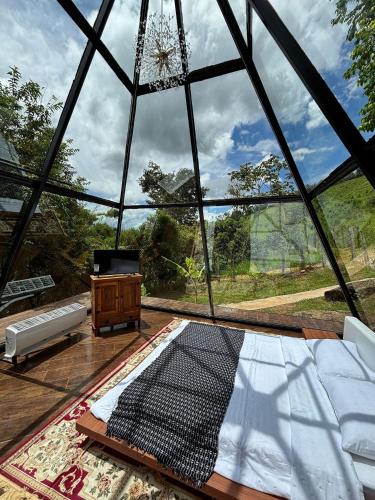 a large glass room with a bed and a table at Piramidevidro in Santa Isabel