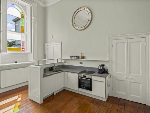 a kitchen with white cabinets and a mirror on the wall at The Music Room in Aveton Gifford