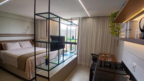 a bedroom with a bed and a glass shelf with a television at Flat no Coração do Recife Próximo ao Consulado Americano in Recife