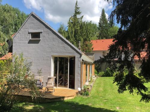 a house with a deck with a chair on it at Cottage near the Mill Pond with a beautiful garden in Le Ponchel