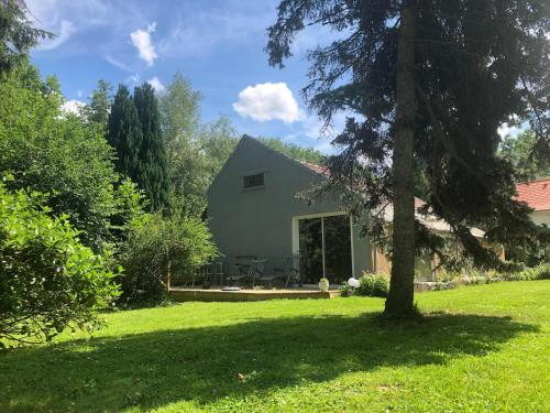 a house in a yard with a tree at Cottage near the Mill Pond with a beautiful garden in Le Ponchel