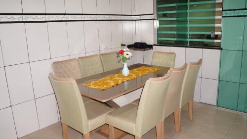a dining room table with chairs and a vase with flowers at Casa compartilhada com Quarto e Suite no Parque 10 in Manaus