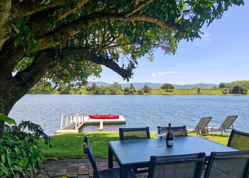 a table and chairs sitting next to a lake at Tweed River Waterfront Cottage in Murwillumbah