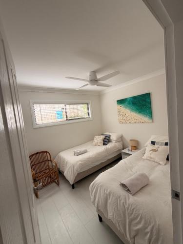 a bedroom with two beds and a ceiling fan at Patonga Street Retreat in Patonga