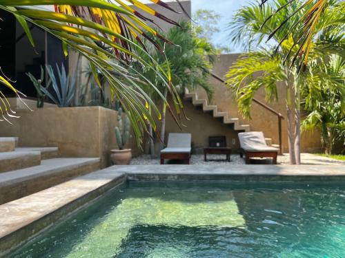 a swimming pool with chairs and stairs next to a house at Casa Maloya alberca y vista al mar in Puerto Escondido