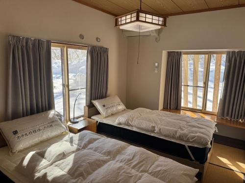 a bedroom with two beds and a large window at 2 Peaks Snow Lodge in Hakuba
